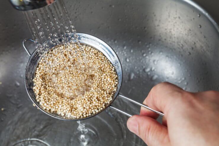Quinoa being rinsed in a fine washer strainer