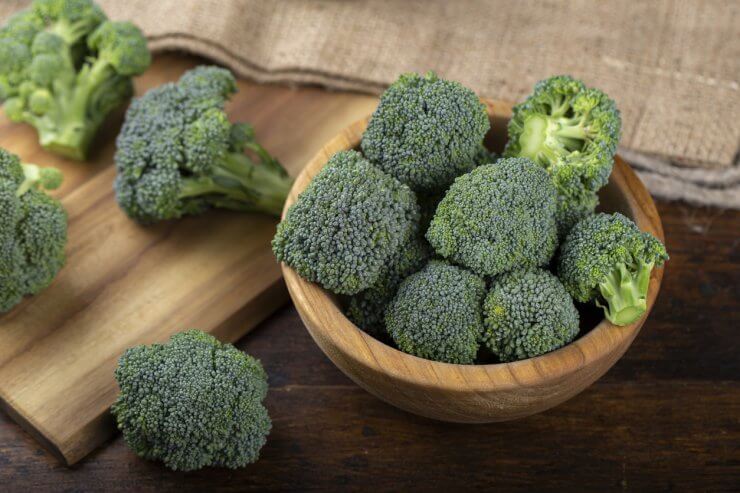 Fresh broccoli in bowl on wooden table