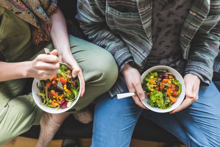 couple eating salad on sofa