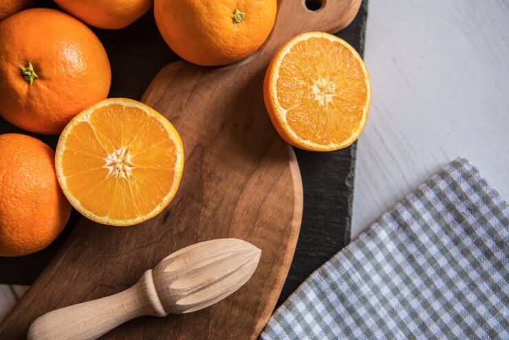 Fresh oranges on cutting board with citrus reamer