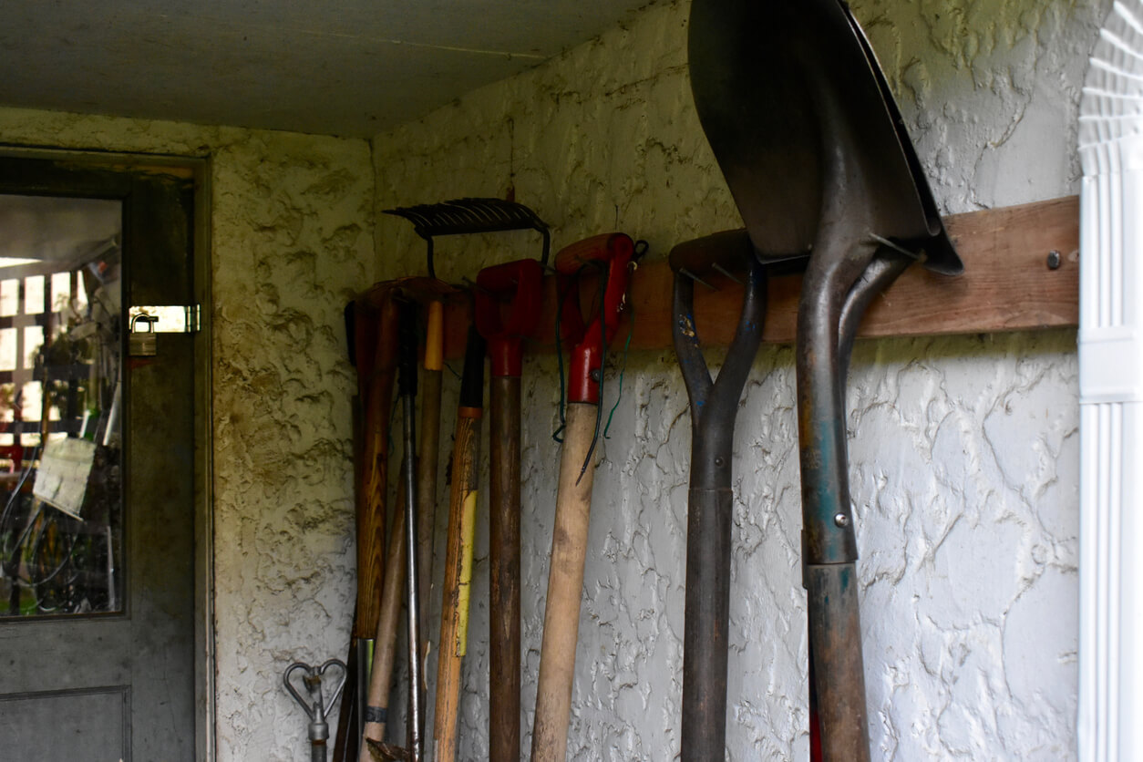Garden tools stored neatly hanging outside working garden shed