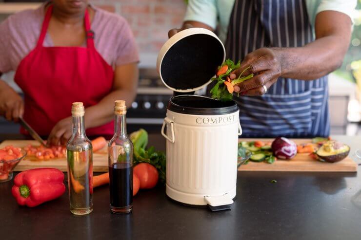 Midsection of african american senior couple cooking together in kitchen using compost bin