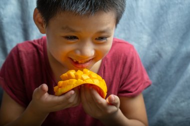 A little boy is eating mango