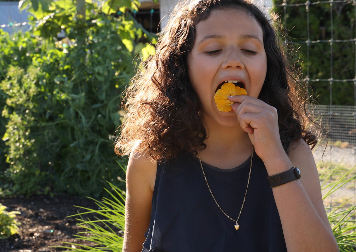 Young girl eats edible flower