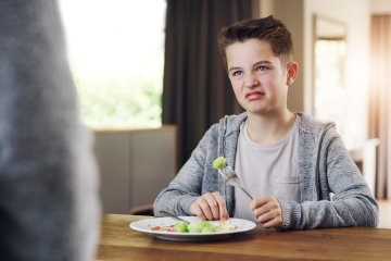 Young boy refusing to eat his brussels sprouts