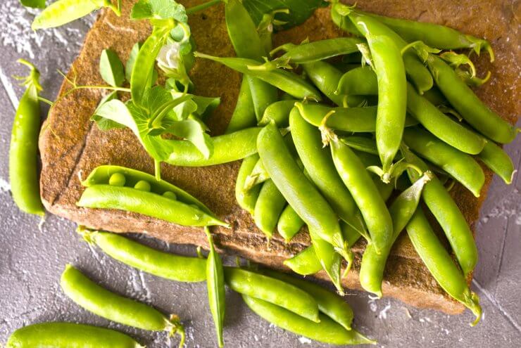 Pods of green peas with leaves