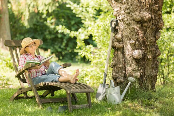 Gardening - senior woman in deck chair enjoy relaxing in garden outdoors