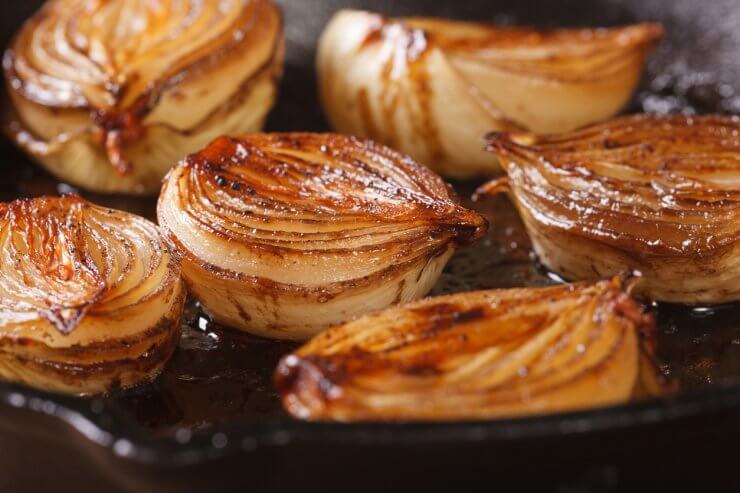 Caramelized onion halves with balsamic vinegar in a pan