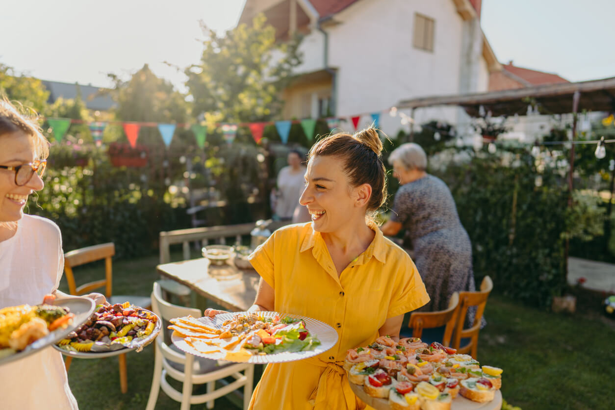 Young women serving food at outdoors dinner party