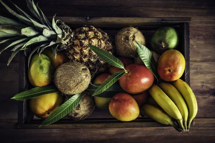 Wooden crates with assorted tropical fruits in rustic kitchen. Natural lighting